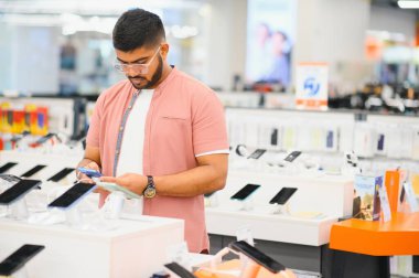 Elektronik mağazasındaki adam cep telefonunu seçiyor..