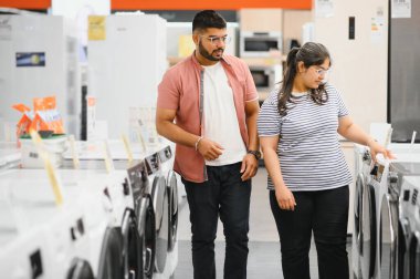 Hintli çift elektronik mağazasından çamaşır makinesini seçiyor.