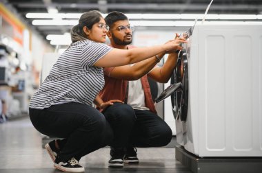 Hintli çift elektronik mağazasından çamaşır makinesini seçiyor.