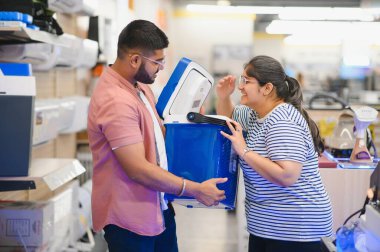 Hintli genç bir çift elektronik mağazasında dinlenmek için plastik bir kutu seçiyor..