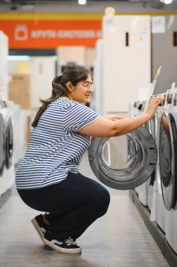 Hintli kadın bir ev aletleri dükkanından buzdolabı seçiyor..