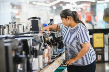 Akıllı modern kadın müşteri elektronik mağazasından kahve makinesi seçimi.