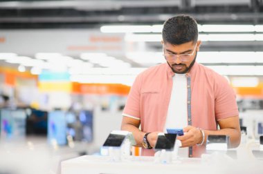 Elektronik mağazasındaki adam cep telefonunu seçiyor..