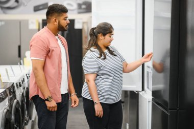 Genç Hintli çift ev aletleri mağazasında yeni buzdolabı seçiyorlar..