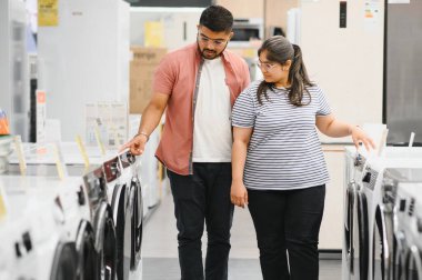 Hintli çift elektronik mağazasından çamaşır makinesini seçiyor.