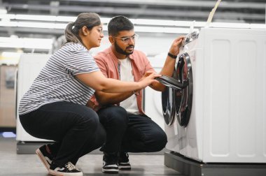 Hintli çift elektronik mağazasından çamaşır makinesini seçiyor.