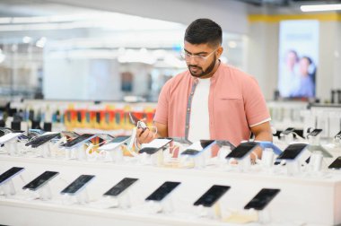 Cep telefonu dükkanındaki Hintli müşteri yeni akıllı telefonunu seçiyor..