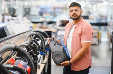 Hintli bir adam elektronik mağazasından yeni bir elektrikli süpürge seçiyor..