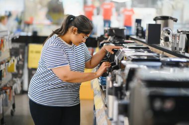 Akıllı modern kadın müşteri elektronik mağazasından kahve makinesi seçimi.