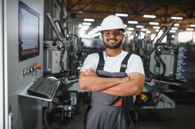 Makine operatörü. Fabrikada sanayi işçisi. Beyaz şapkalı genç teknisyen..