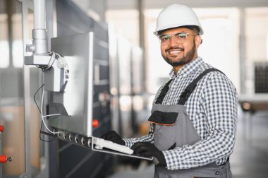 Portrait Indian male staff worker engineer supervisor in safety suit work in factory warehouse.