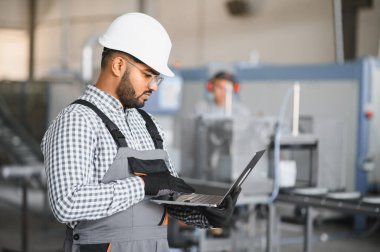 Fabrikada güvenlik önlüğü giyen mutlu Hintli erkek mühendis..