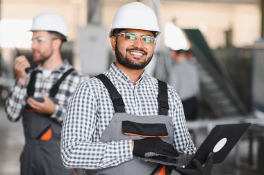 Elleri dizüstü bilgisayarı tutarken Hintli erkek mühendisin portresi fabrikaya girdi..