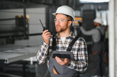 Gülümseyen ve mutlu çalışan. Fabrikadaki endüstriyel işçilerin portresi. Beyaz şapkalı genç teknisyen..