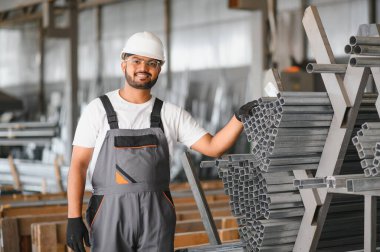 Gülümseyen ve mutlu çalışan. Fabrikada sanayi işçisi. Turuncu şapkalı genç teknisyen..
