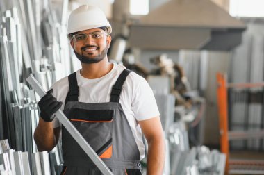 Gülümseyen ve mutlu çalışan. Fabrikada sanayi işçisi. Turuncu şapkalı genç teknisyen..