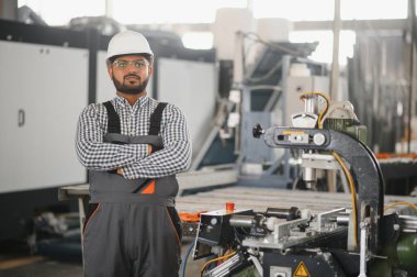 Makine operatörü. Fabrikada sanayi işçisi. Beyaz şapkalı genç teknisyen..