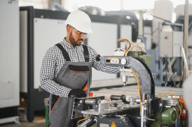 Makine operatörü. Fabrikada sanayi işçisi. Beyaz şapkalı genç teknisyen..