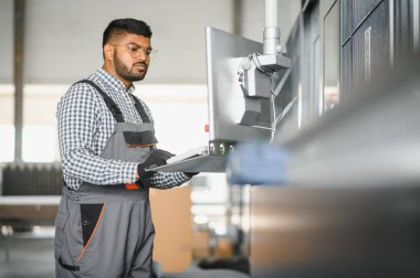 Makine operatörü. Fabrikada sanayi işçisi. Beyaz şapkalı genç teknisyen..