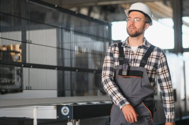 Gülümseyen ve mutlu çalışan. Fabrikadaki endüstriyel işçilerin portresi. Beyaz şapkalı genç teknisyen..