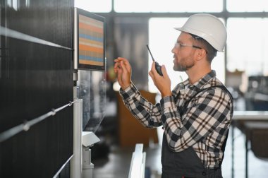 Fabrika erkek sakallı işçi bir CNC değirmen makinesini kopyalama alanı ile programlıyor..