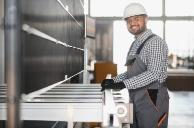 Portrait Indian male staff worker engineer supervisor in safety suit work in factory warehouse.
