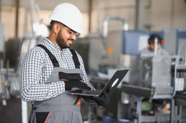 Elleri dizüstü bilgisayarı tutarken Hintli erkek mühendisin portresi fabrikaya girdi..