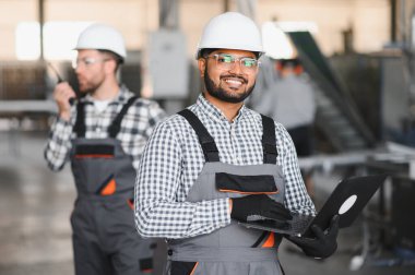 Elleri dizüstü bilgisayarı tutarken Hintli erkek mühendisin portresi fabrikaya girdi..