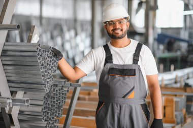 Modern fabrikada şapka takan neşeli genç işçilerin portresi..