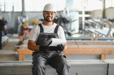 Portrait Indian male staff worker engineer supervisor in safety suit work in factory warehouse.