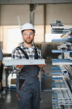 Fabrika işçisi. Miğferli adam PVC ile çalışıyor..