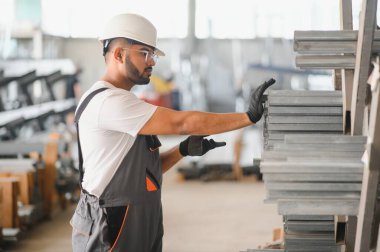 Modern fabrikada şapka takan neşeli genç işçilerin portresi..