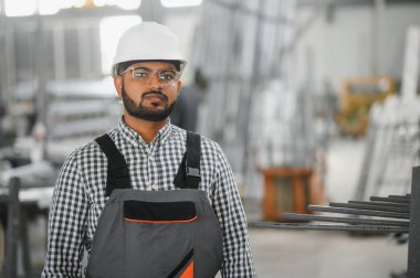 Fabrikada güvenlik önlüğü giyen mutlu Hintli erkek mühendis..