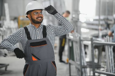 Fabrikada güvenlik önlüğü giyen mutlu Hintli erkek mühendis..