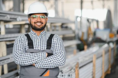 Modern fabrikada şapka takan neşeli genç işçilerin portresi..