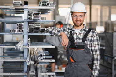 Gülümseyen ve mutlu çalışan. Fabrikadaki endüstriyel işçilerin portresi. Beyaz şapkalı genç teknisyen..