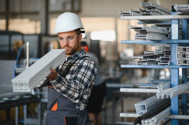 Fabrika işçisi. Miğferli adam PVC ile çalışıyor..
