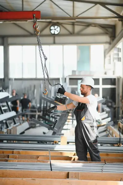 stock image Portrait of a young worker in a hard hat at a large metalworking factory. Shiftman on the warehouse of finished products.