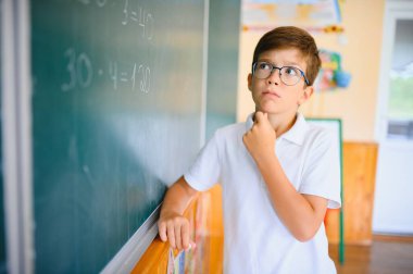 Sınıfta tahtaya yakın sevimli bir okul çocuğu..