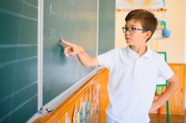 Sınıfta tahtaya yakın sevimli bir okul çocuğu..