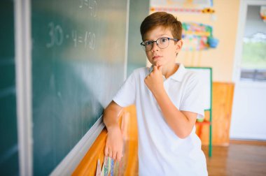 Sevimli küçük okul çocuğunun fotoğrafı tebeşir yaz matematik problemini çöz şık üniformalı sınıf karatahta arka planı