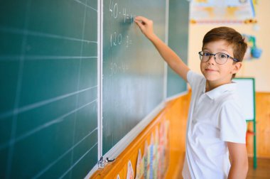 Sınıfta tahtaya yakın sevimli bir okul çocuğu..