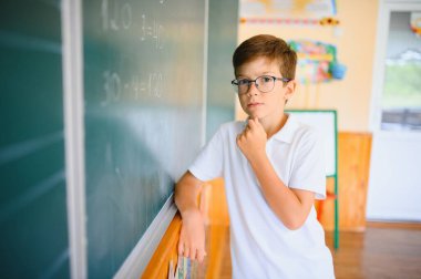 Sınıfta tahtaya yakın sevimli bir okul çocuğu..