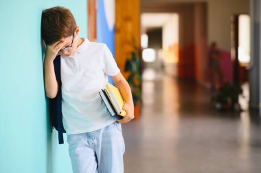 Okul zorbalığı. Okul koridorunda bir çocuk duvara karşı ağlıyor..