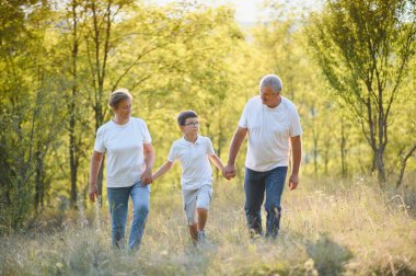 Torunum, büyükbabam ve büyükannem çimlerin üzerinde oturmuş gün batımında parkta eğleniyorlar..