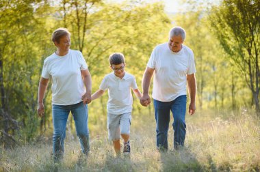 Büyük anne ve büyük baba yaz günbatımında torunlarıyla yürüyorlar..