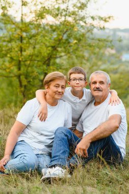 Torunlarının yanında dedeleri. Çayırlarda oynuyorlar ve gün batımında eğleniyorlar..