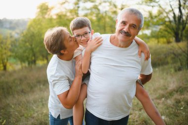 Büyük anne ve büyük baba yaz günbatımında torunlarıyla yürüyorlar..
