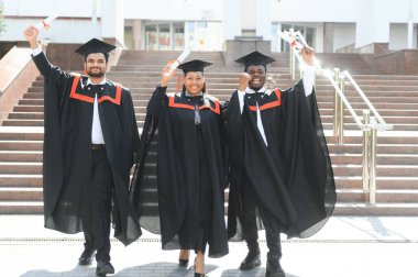 Üniversite kampüsünde diplomalı çeşitli uluslararası öğrenciler.