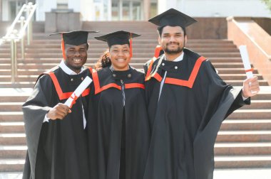 Üniversite kampüsünde diplomalı çeşitli uluslararası öğrenciler.